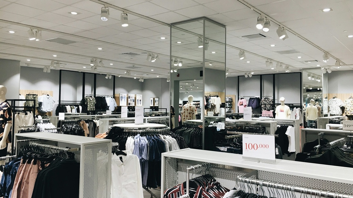 Winkelinterieur van een keten met gestructureerde kledingrekken en overzichtelijke presentatie van herenkleding
