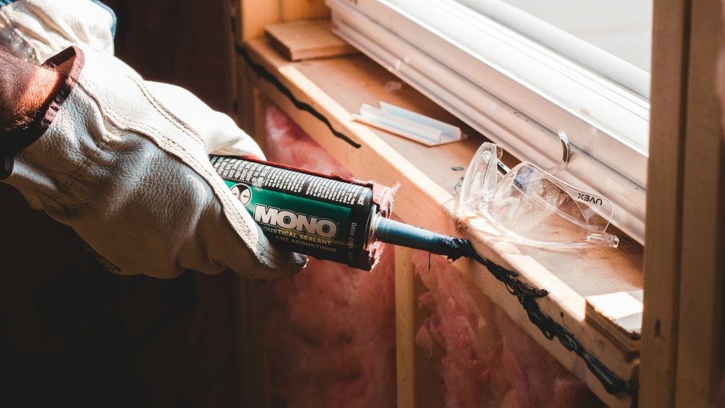 Kit wordt aangebracht rond kozijn tijdens onderhoudswerkzaamheden