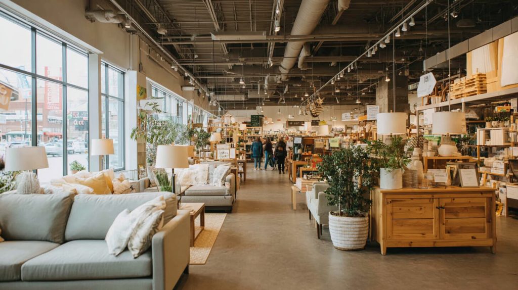 Kringloopwinkel met sfeervol ingerichte tweedehands meubels, lampen en woonaccessoires, waar bezoekers rondkijken tussen de schappen