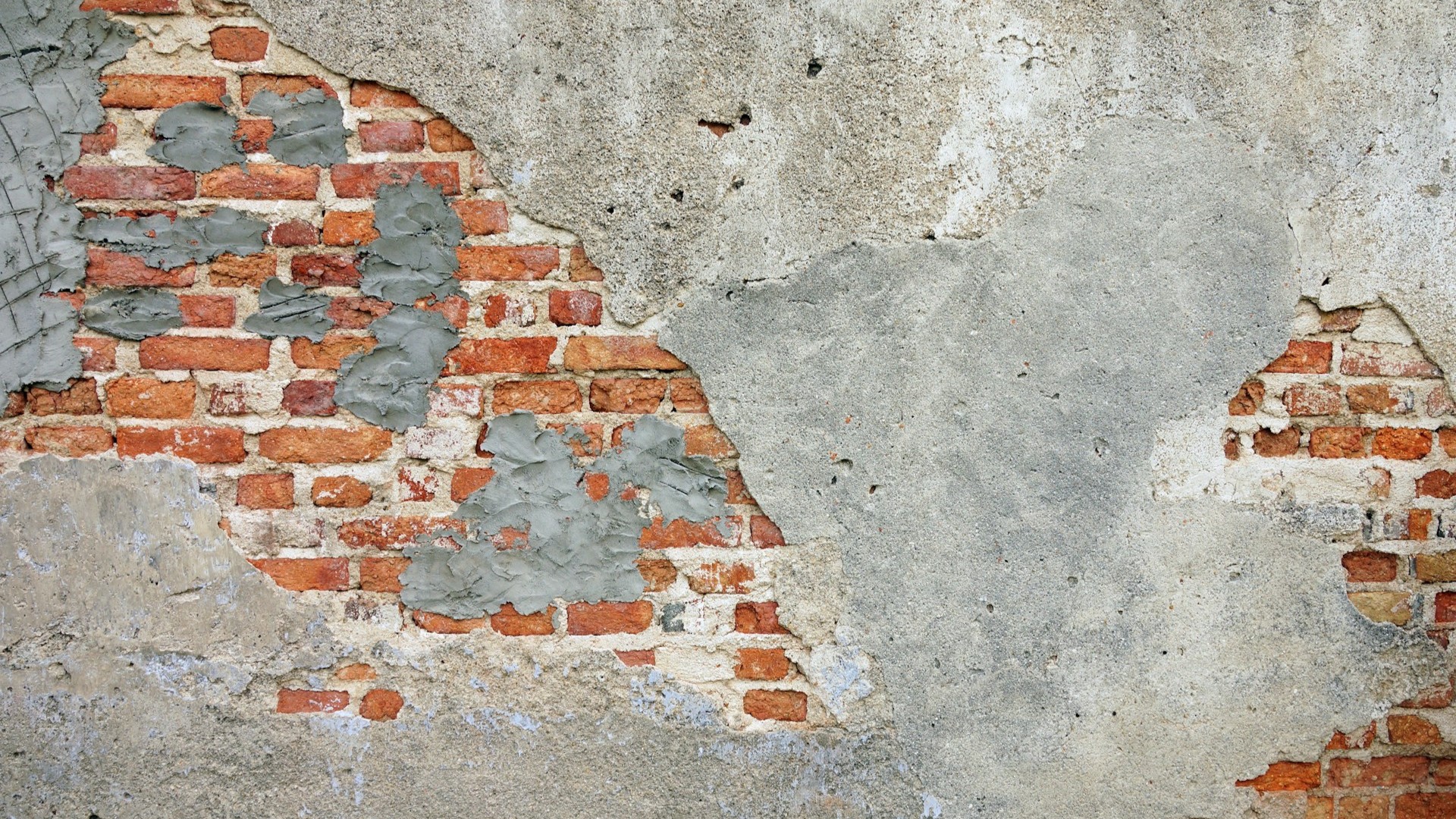Oude bakstenen muur met afbrokkelend pleisterwerk en verse cementplekken, een voorbeeld van gebruikte bouwmaterialen bij een verbouwing
